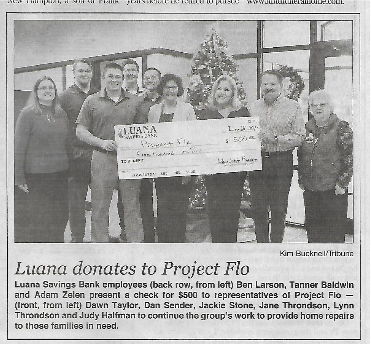 Group photo of Luana Savings Bank employees and Project Flo representatives holding a large novelty check for $500.